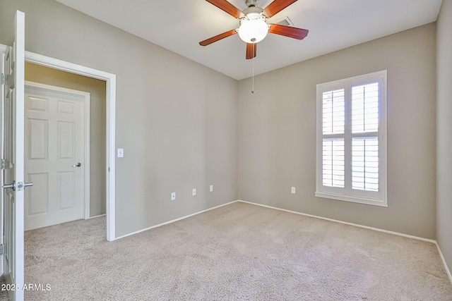 carpeted empty room featuring baseboards and a ceiling fan