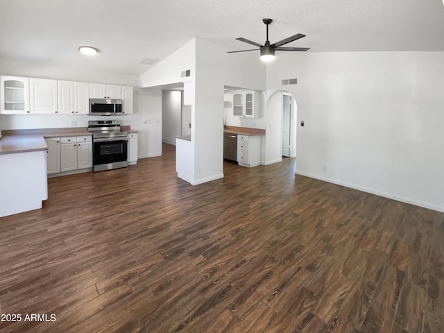 kitchen featuring appliances with stainless steel finishes, open floor plan, vaulted ceiling, dark wood-type flooring, and visible vents
