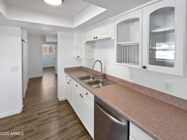 kitchen featuring dishwasher, a sink, baseboards, a tray ceiling, and dark wood-type flooring