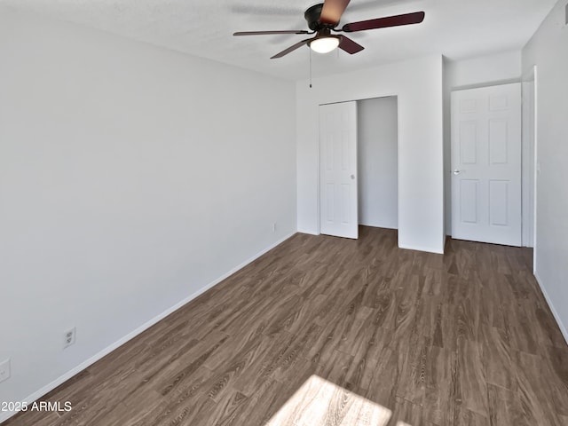 unfurnished bedroom featuring a closet, baseboards, and dark wood-type flooring