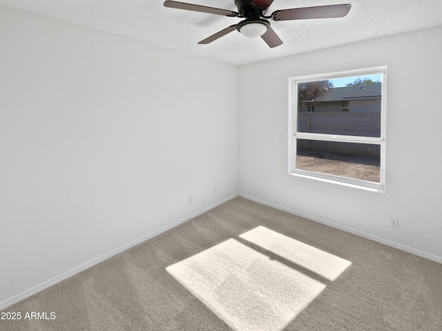 carpeted spare room featuring baseboards and ceiling fan