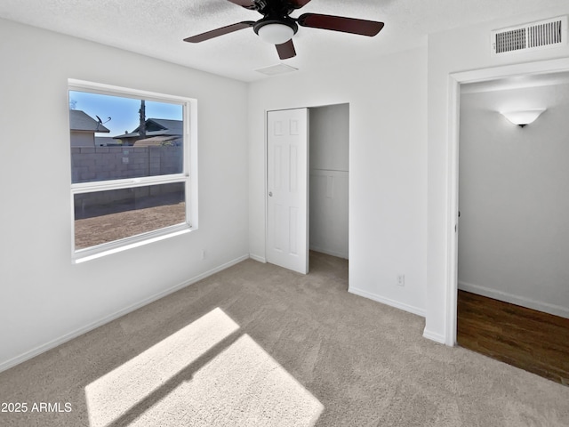 unfurnished bedroom featuring carpet floors, baseboards, a closet, and visible vents