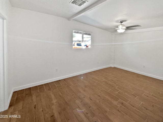 spare room featuring wood finished floors, ceiling fan, beam ceiling, and visible vents