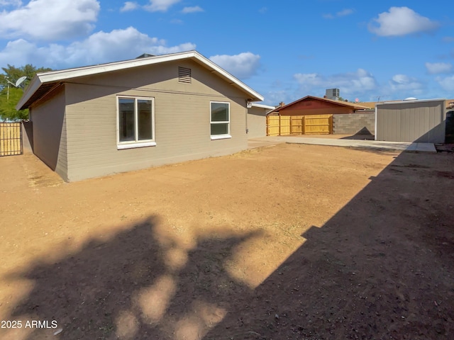 rear view of house with an outbuilding, fence, and a storage shed