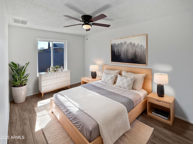 bedroom with baseboards, a ceiling fan, wood finished floors, and visible vents