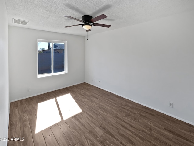 empty room featuring a textured ceiling, a ceiling fan, baseboards, wood finished floors, and visible vents