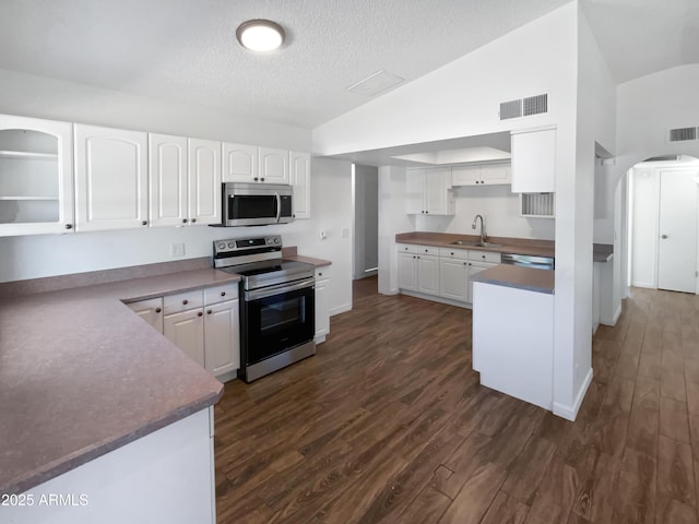 kitchen featuring visible vents, lofted ceiling, arched walkways, a sink, and appliances with stainless steel finishes