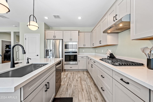 kitchen with white cabinets, decorative light fixtures, light hardwood / wood-style flooring, and sink