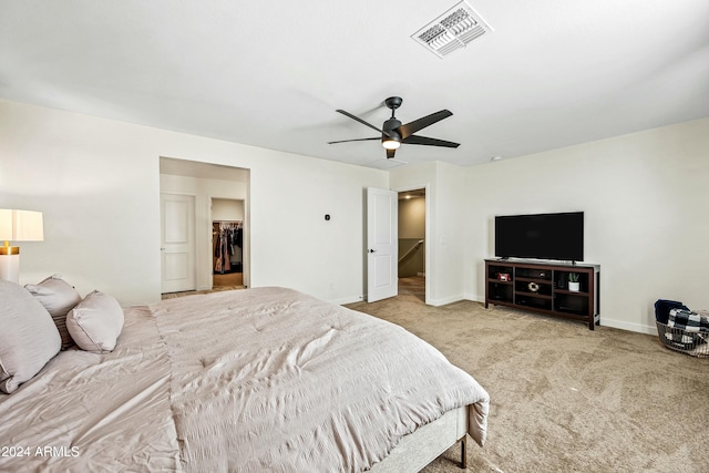 bedroom featuring ceiling fan, a closet, light colored carpet, and a spacious closet