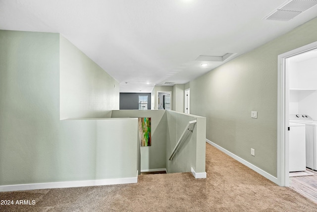 hall with separate washer and dryer and light carpet