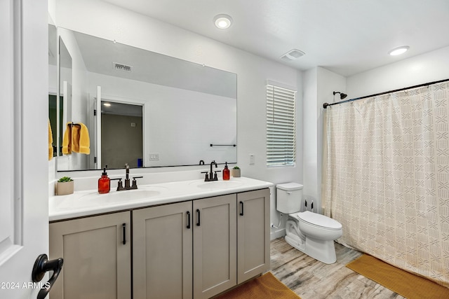 bathroom featuring hardwood / wood-style floors, vanity, toilet, and walk in shower