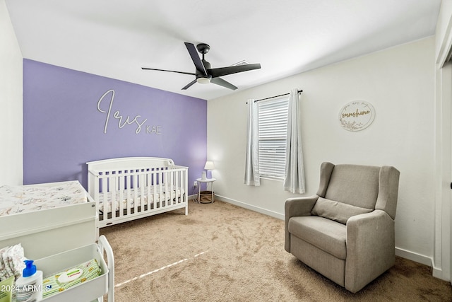 carpeted bedroom featuring ceiling fan and a crib