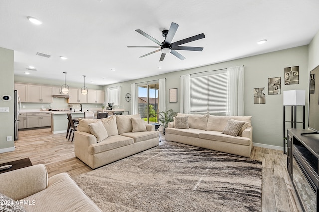 living room with ceiling fan and light hardwood / wood-style flooring