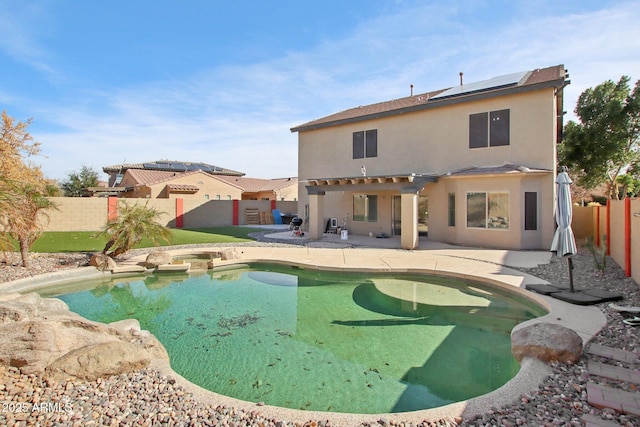 rear view of house featuring a patio area, a fenced backyard, solar panels, and stucco siding