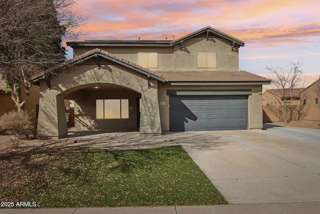 view of front of house featuring a garage, a tiled roof, concrete driveway, and stucco siding