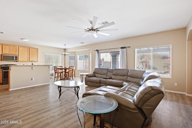 living area with baseboards, visible vents, light wood finished floors, and ceiling fan with notable chandelier