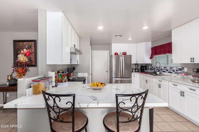 kitchen with a kitchen island, light stone countertops, appliances with stainless steel finishes, and a breakfast bar