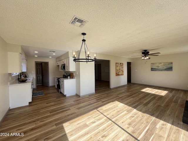 unfurnished living room with wood-type flooring, ceiling fan with notable chandelier, and a textured ceiling