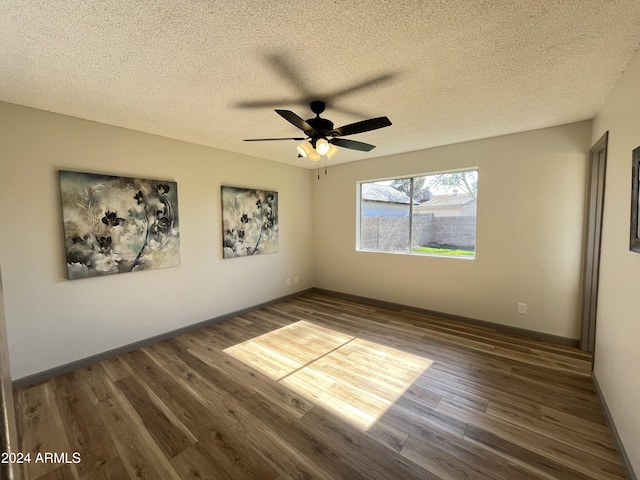 empty room with dark hardwood / wood-style floors, ceiling fan, and a textured ceiling