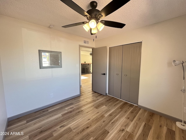 unfurnished bedroom with a closet, ceiling fan, hardwood / wood-style floors, and a textured ceiling