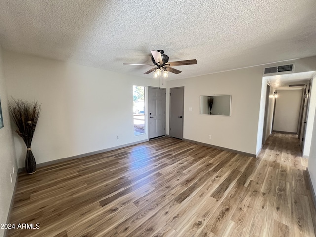 empty room with ceiling fan, hardwood / wood-style floors, and a textured ceiling