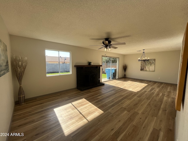 unfurnished living room featuring a fireplace, dark hardwood / wood-style flooring, ceiling fan with notable chandelier, and a textured ceiling