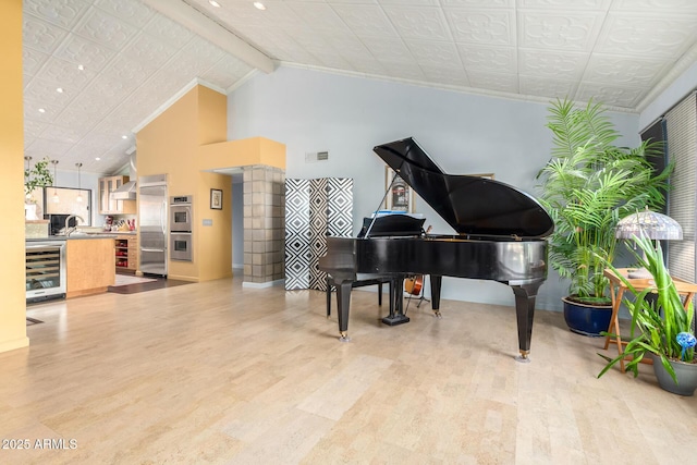 living area with sink, light hardwood / wood-style flooring, high vaulted ceiling, and beverage cooler