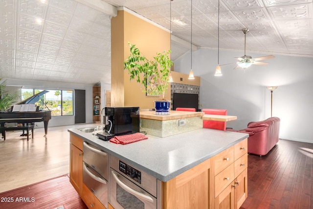 kitchen with lofted ceiling, a kitchen island with sink, light brown cabinetry, and dark hardwood / wood-style flooring