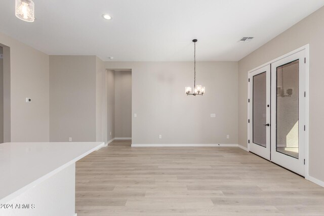 empty room with light hardwood / wood-style flooring and a notable chandelier