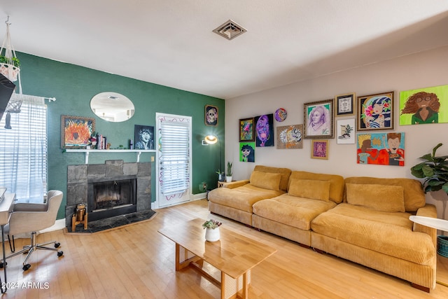 living room with hardwood / wood-style flooring and a stone fireplace