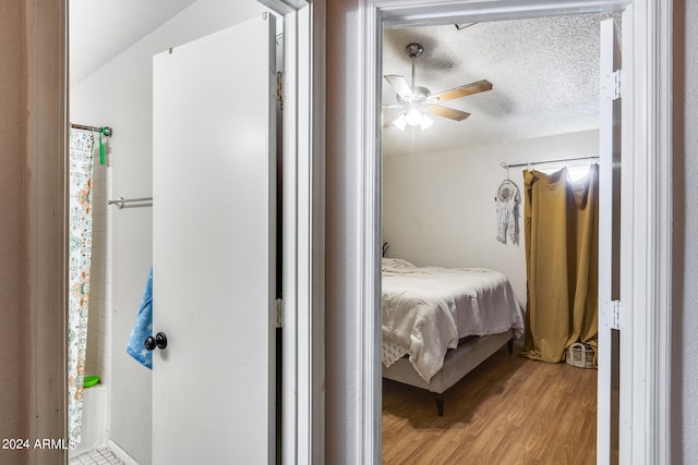 bedroom with lofted ceiling, a textured ceiling, ceiling fan, and light wood-type flooring