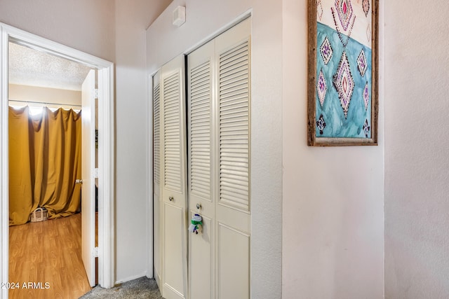 corridor with a textured ceiling and hardwood / wood-style floors