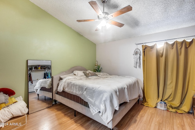 bedroom featuring hardwood / wood-style floors, a closet, vaulted ceiling, ceiling fan, and a textured ceiling