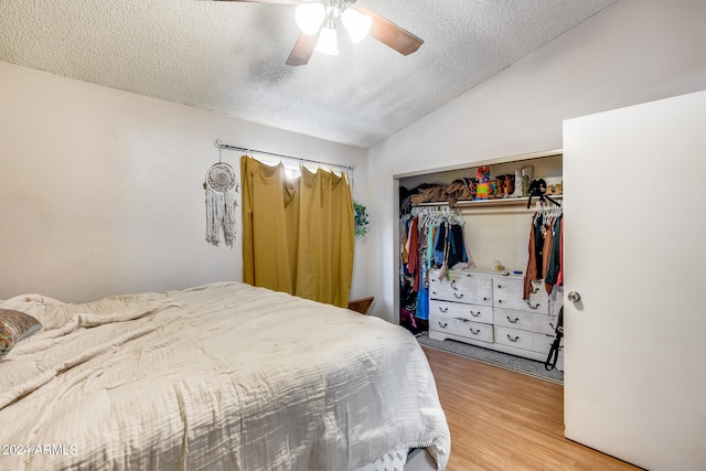 bedroom with light wood-type flooring, a textured ceiling, ceiling fan, and a closet