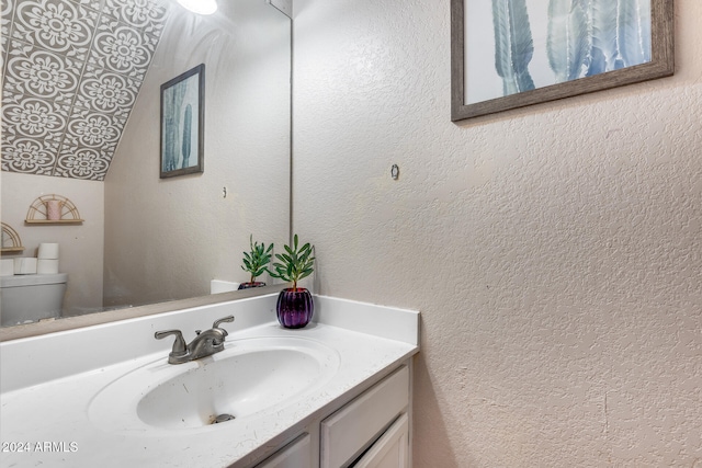 bathroom featuring lofted ceiling, toilet, and vanity