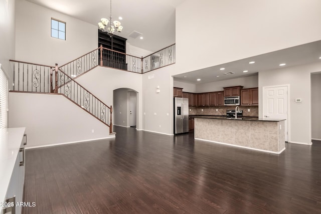 10910 E Sebring Ave, Mesa, AZ 85212 - unfurnished living room with arched walkways, dark wood-type flooring, a chandelier, a towering ceiling, and recessed lighting