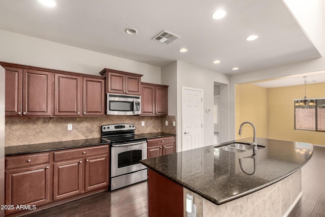 10910 E Sebring Ave, Mesa, AZ 85212 - kitchen featuring stainless steel appliances, dark wood finished floors, decorative backsplash, dark stone countertops, and a kitchen island with sink