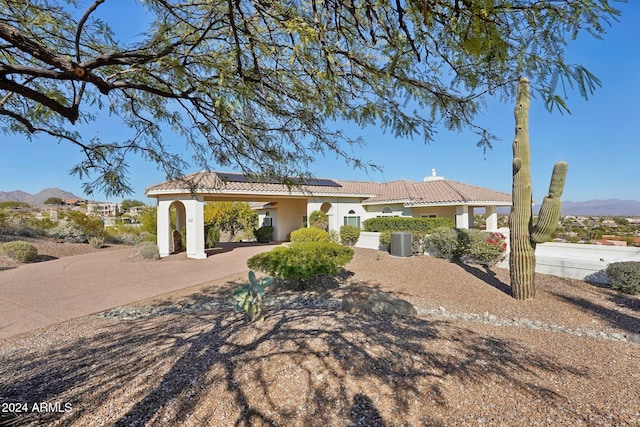 view of front of property with a mountain view, ceiling fan, and solar panels