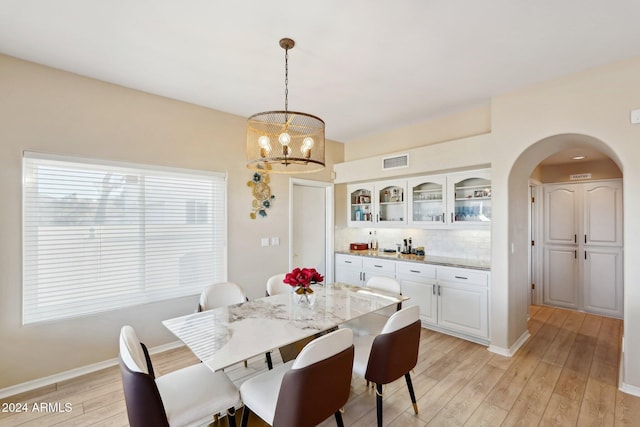 dining area with light hardwood / wood-style floors and an inviting chandelier