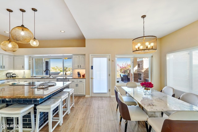 dining space featuring sink, light hardwood / wood-style flooring, plenty of natural light, and a notable chandelier