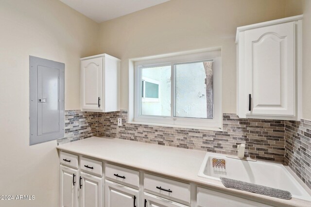 kitchen featuring white cabinetry, electric panel, and tasteful backsplash