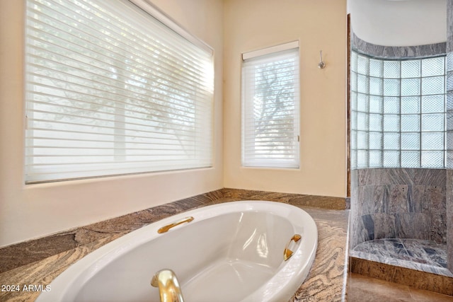 bathroom with plenty of natural light and tiled bath