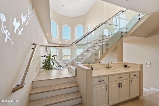 stairway featuring sink and a towering ceiling