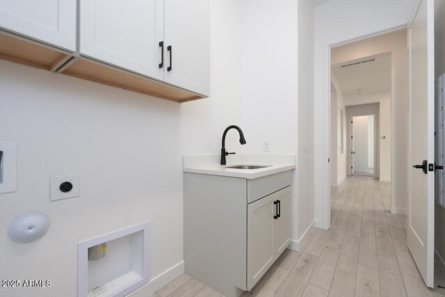 laundry room featuring cabinets, sink, light hardwood / wood-style floors, and hookup for an electric dryer