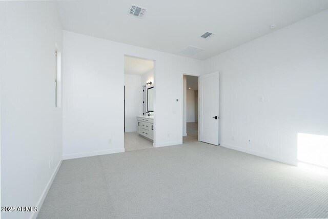 unfurnished bedroom featuring ensuite bathroom and light colored carpet