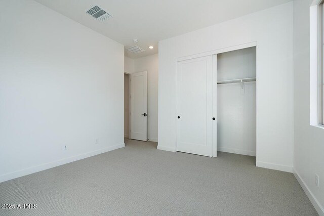 unfurnished bedroom featuring a closet and light colored carpet