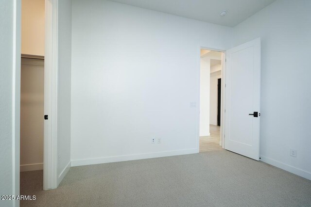 unfurnished bedroom featuring light carpet, a walk in closet, and a closet