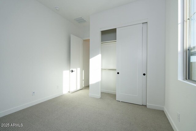 unfurnished bedroom with multiple windows, a closet, and light colored carpet