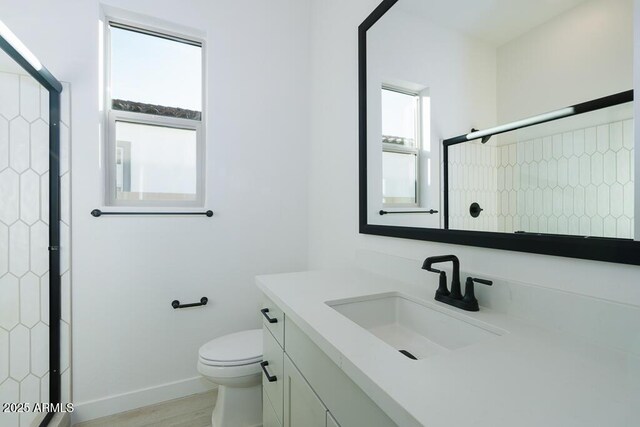 bathroom with toilet, a wealth of natural light, wood-type flooring, and vanity