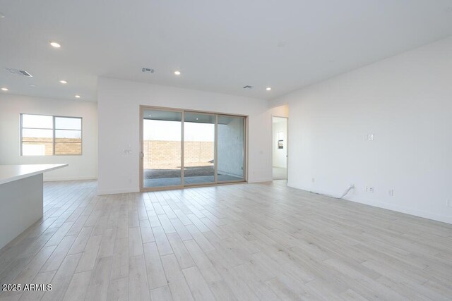 empty room with plenty of natural light and light hardwood / wood-style floors